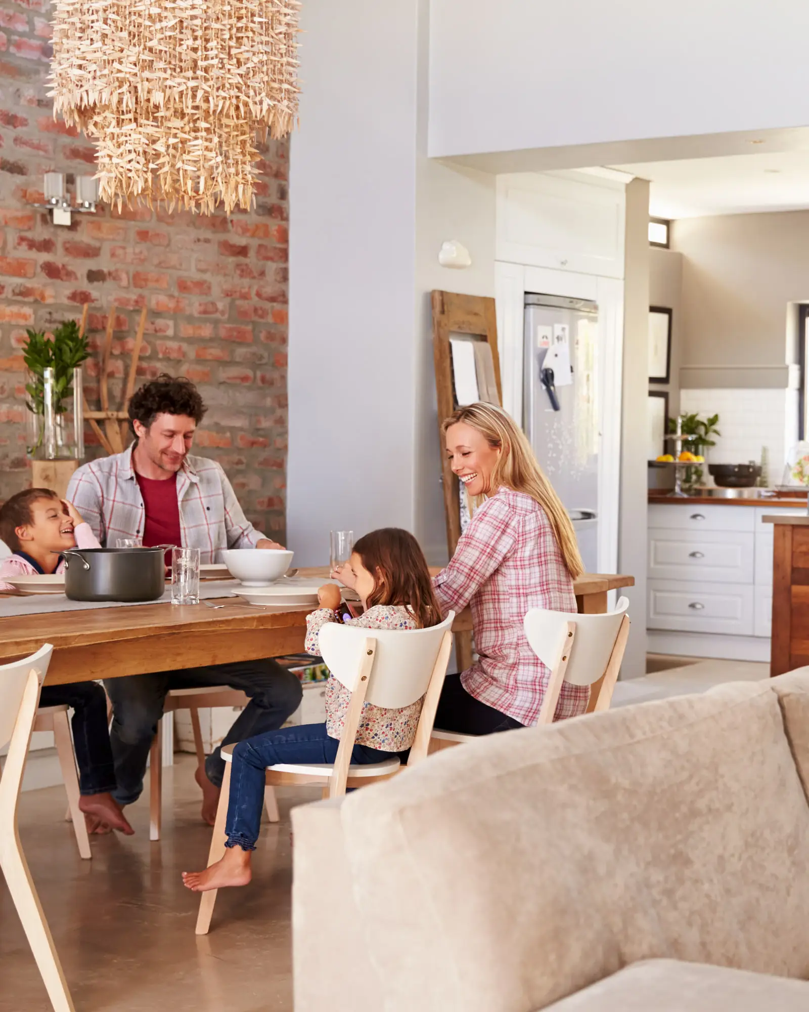 A family of four eating together at a wooden table in a bright, uncluttered open-plan kitchen